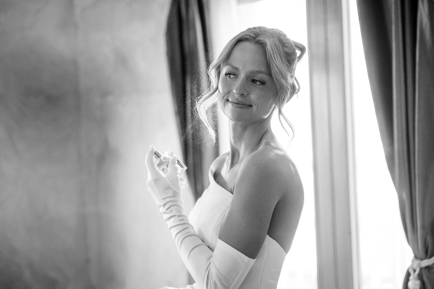 A bride in a white wedding dress poses elegantly by a window with natural light streaming in at at Villa Antonia