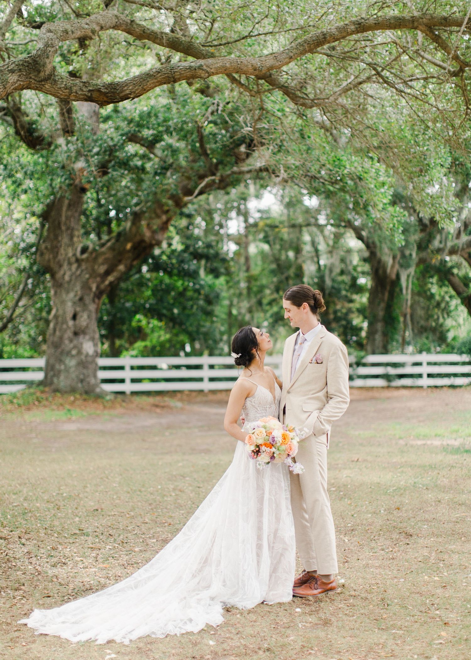 Couple posing under mossy oak and Spanish moss in Charleston, South Carolina for their wedding photographer in lowcountry wedding.