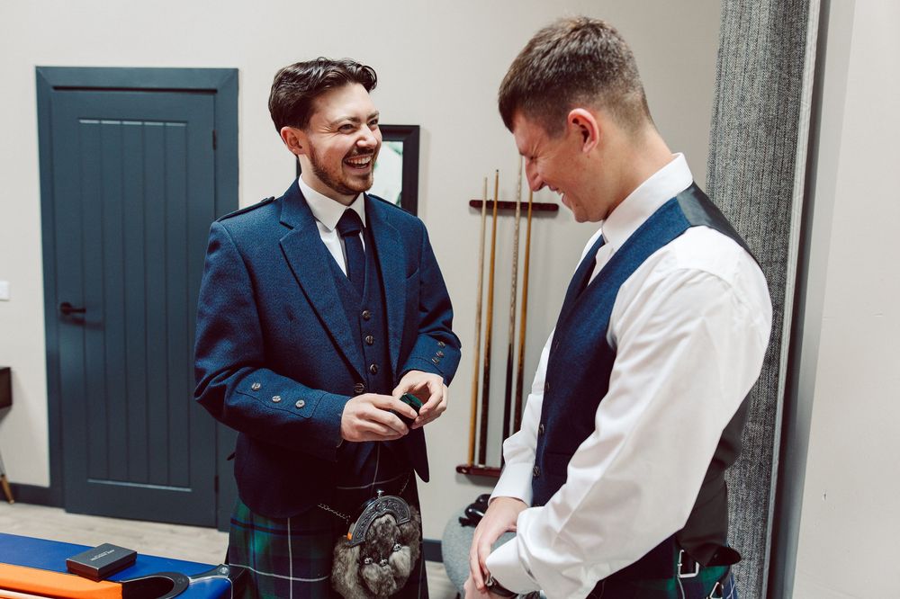 Two people in formal attire stand together while looking at documents during a business meeting.