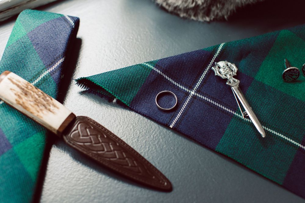 Close-up view of a leather craftsman's workspace with tools, patterns, and materials arranged on a green surface.