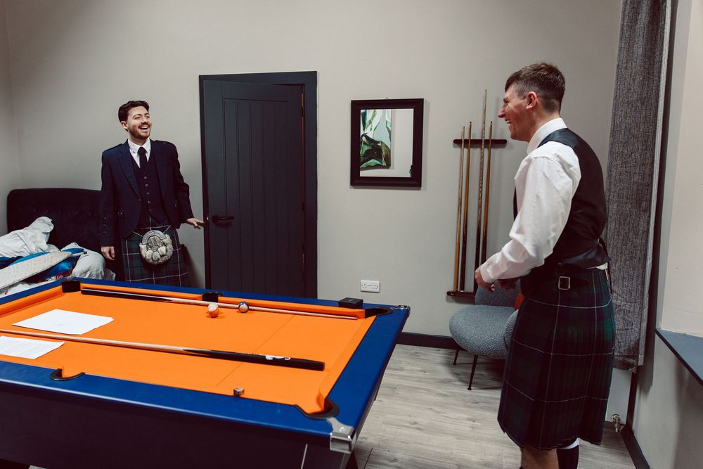 Players compete in a professional pool tournament at a billiards hall with orange felt tables and blue rails.