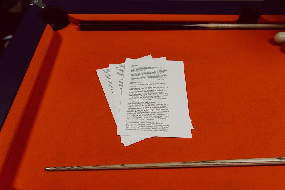 Multiple papers and documents laid out on a bright red-orange surface with what appears to be a metal rod or tool.