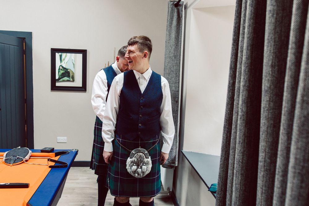 Professional tailors in formal attire work on measuring and fitting garments in an elegant clothing shop.