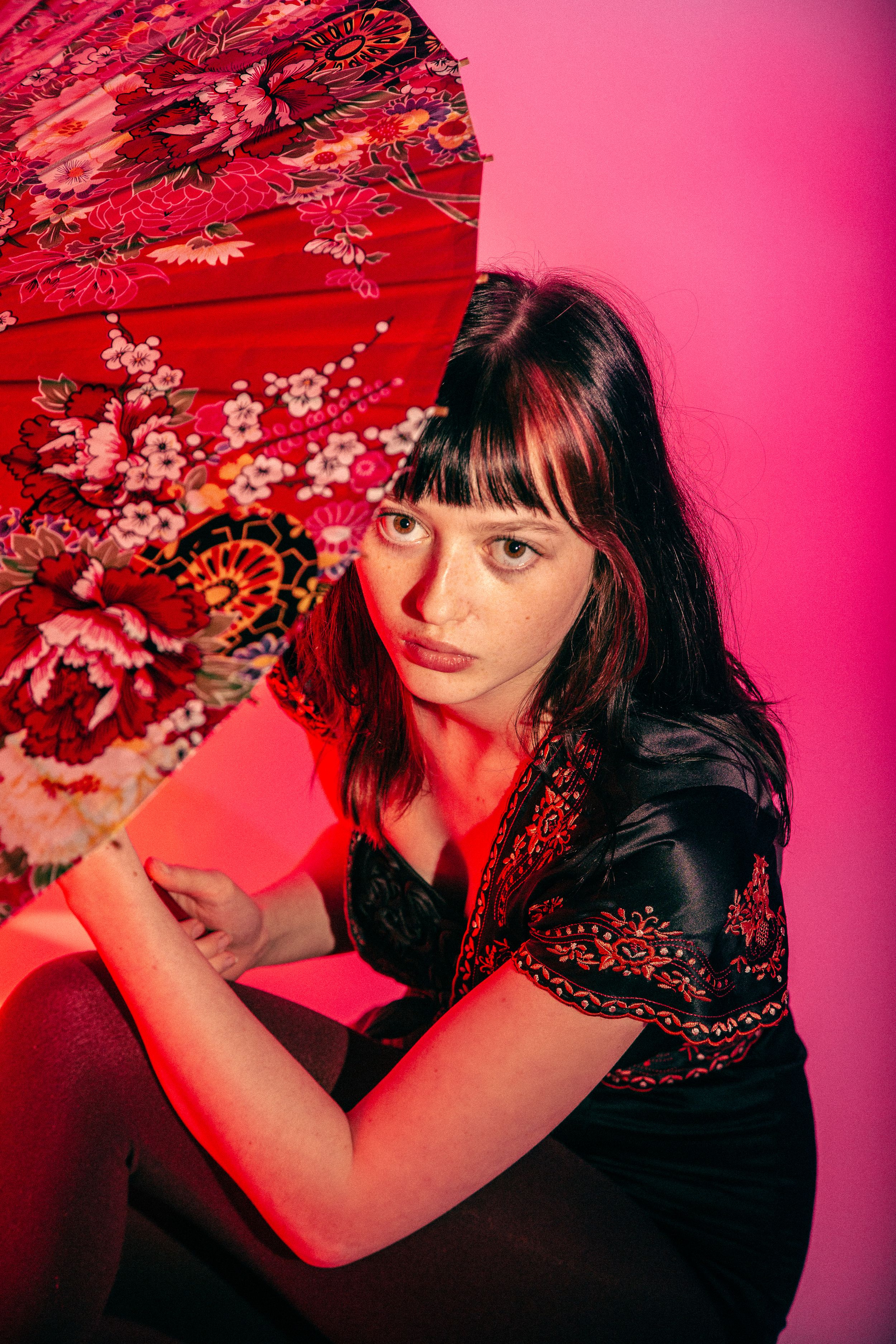 Artistic photo series in vibrant red lighting featuring a decorative floral parasol against a pink backdrop.