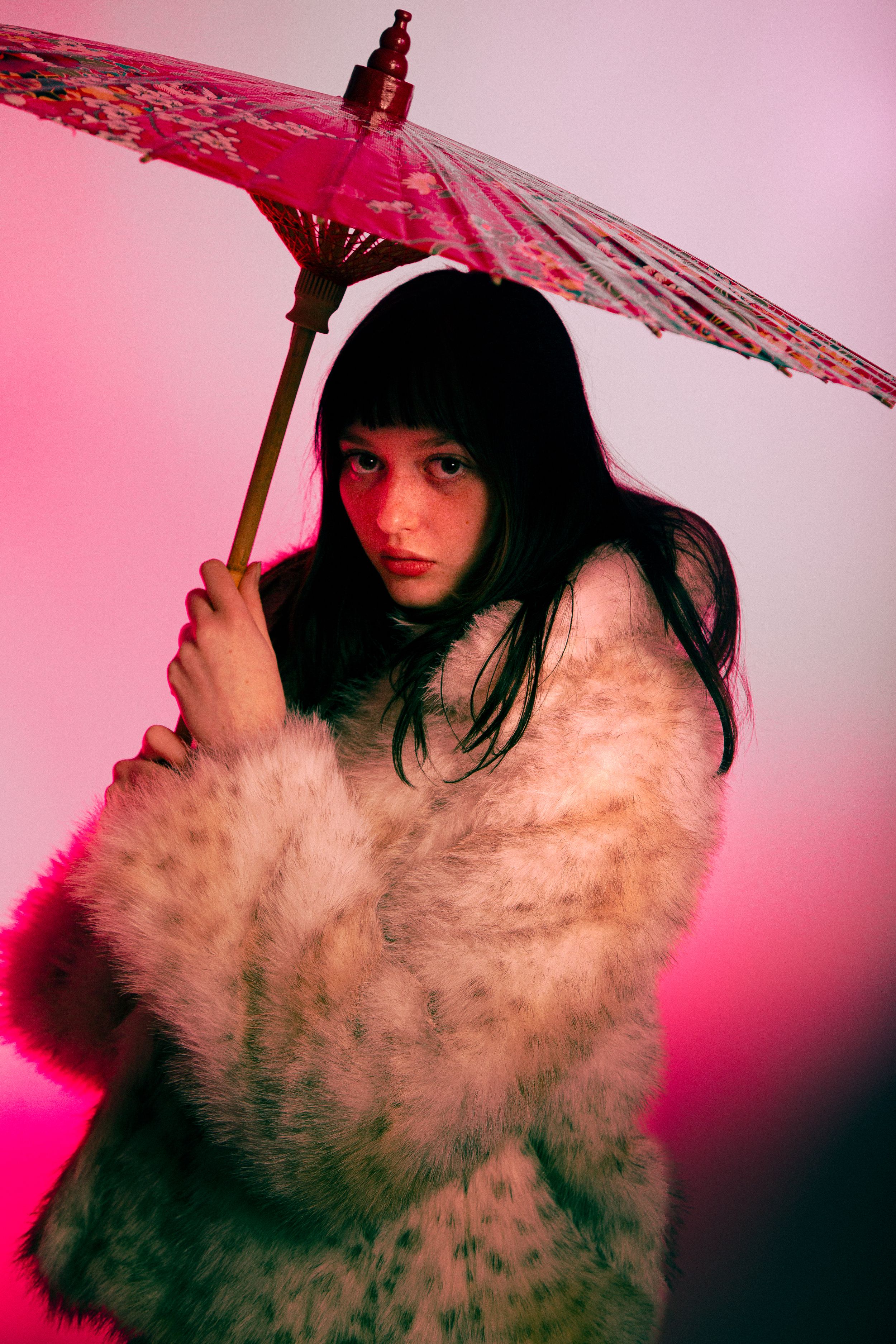 Artistic portrait series with parasol against pink background showing motion and smoke effects in dramatic lighting.