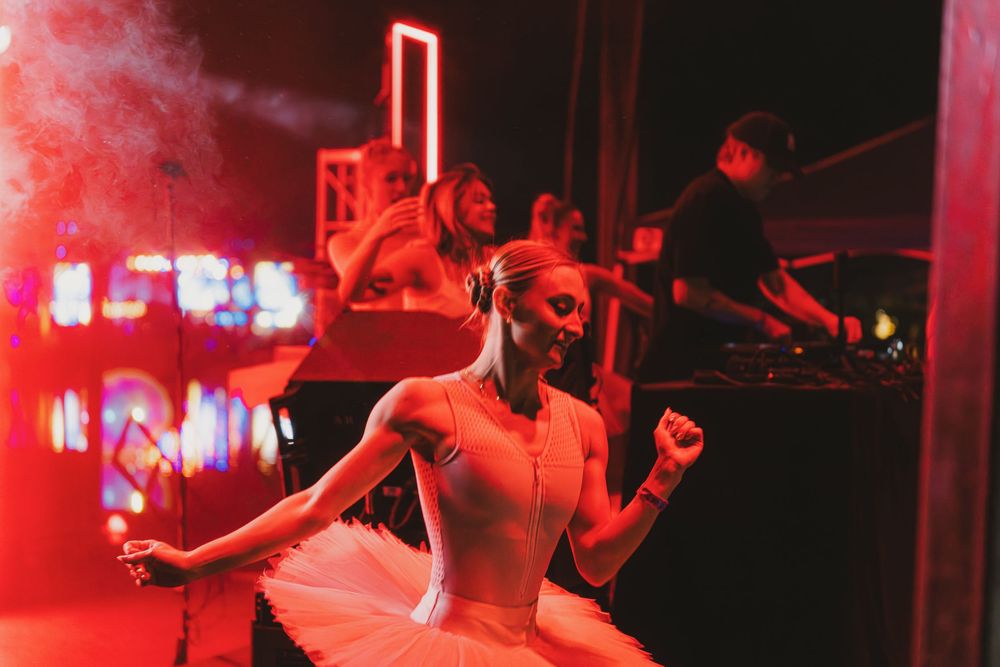 Energetic performers on stage bathed in intense red lighting create an atmospheric concert scene.