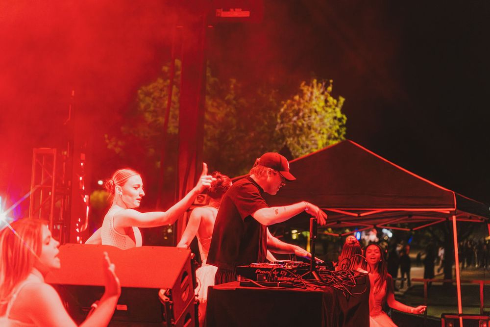 Musicians perform on stage bathed in dramatic red lighting during a live concert performance.