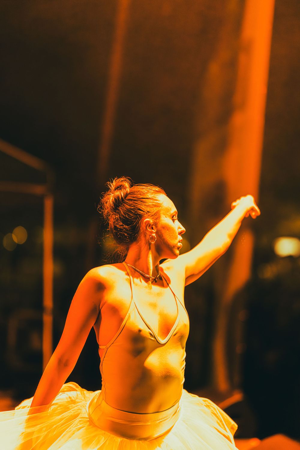A dancer performs an energetic movement sequence in warm orange lighting on stage during a performance.