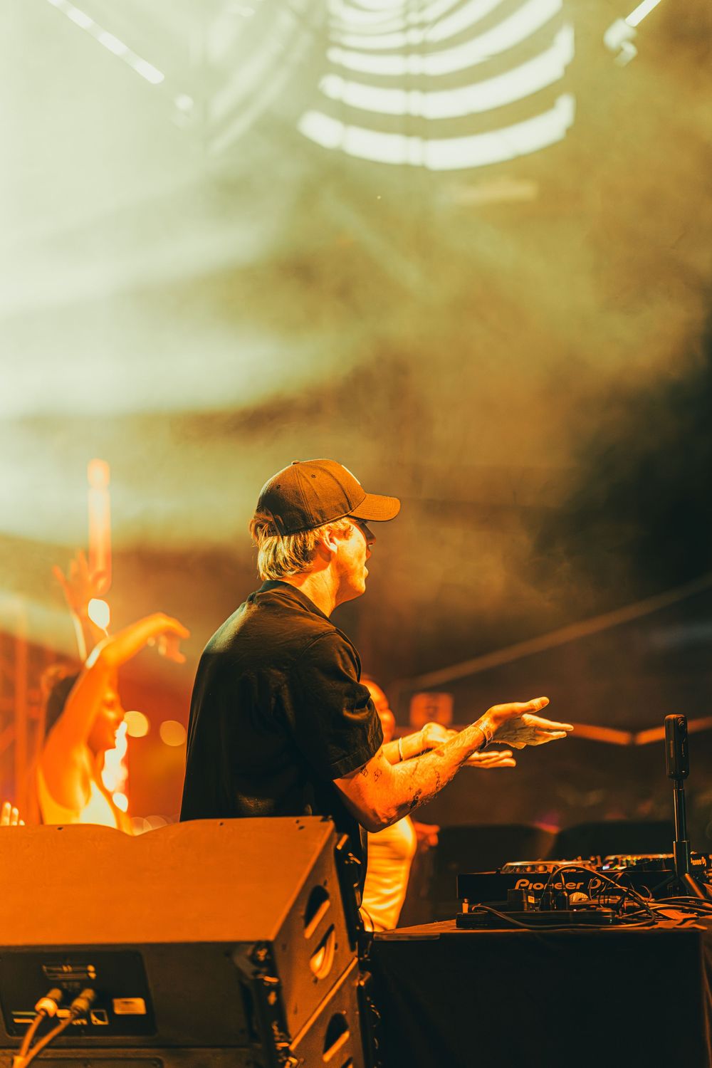 DJ performs at an electronic music concert with dramatic orange lighting and smoke effects on stage.
