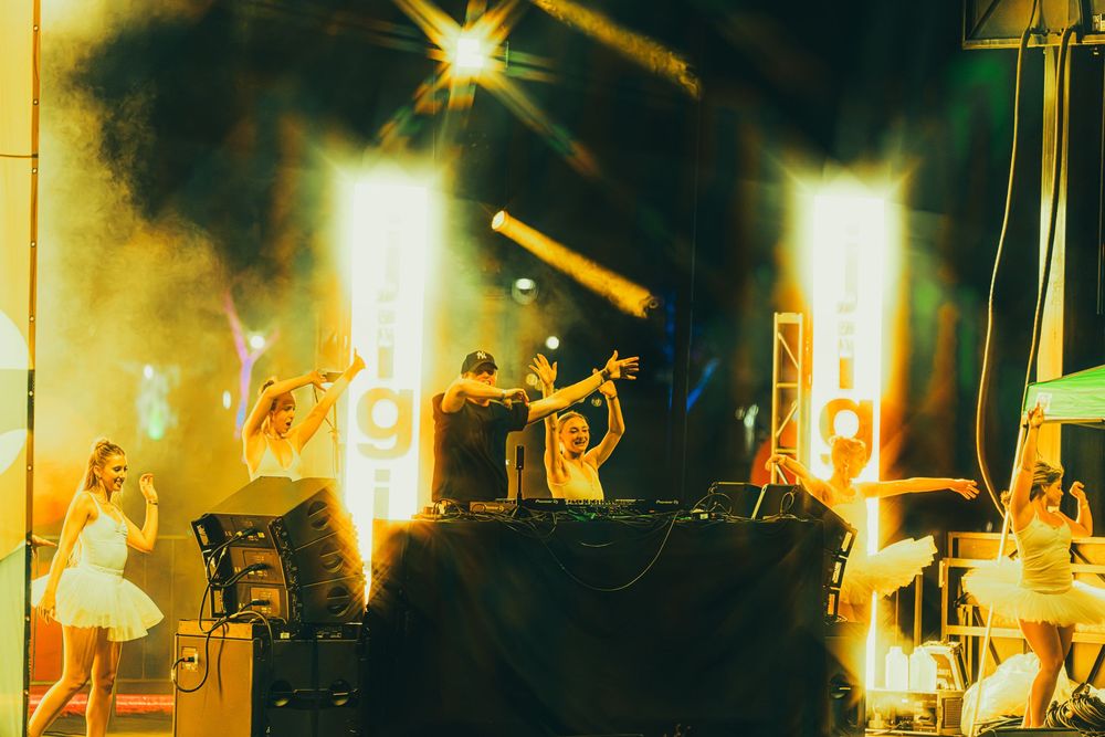 Concert performers on stage illuminated by dramatic yellow lighting during a nighttime music performance.