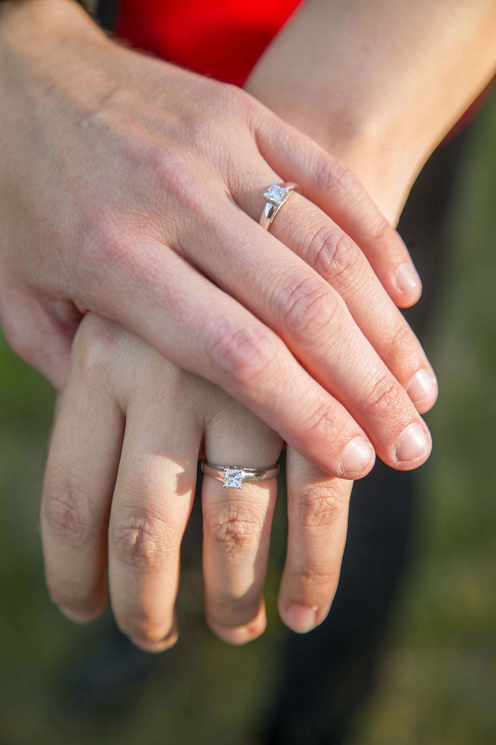 Close-up of hands displaying matching engagement and wedding rings.