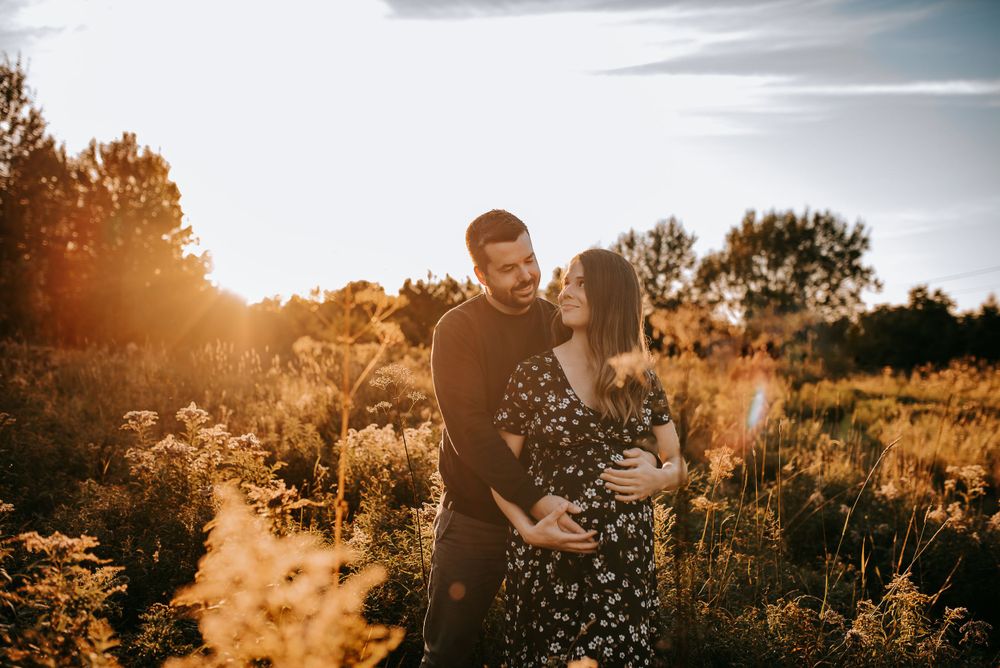 A couple embraces in a sunlit field during golden hour.