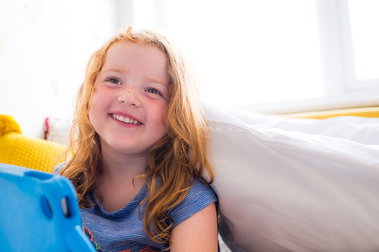 Happy playtime with blue toys and white bedding.