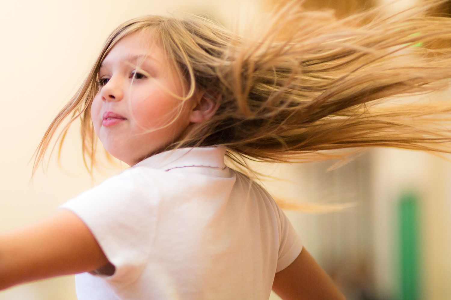 Blonde hair flows dramatically through the air as someone spins and dances in a white t-shirt.