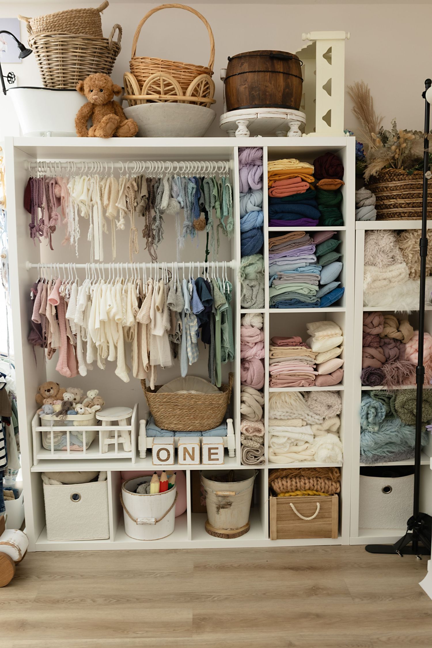 Selection of neutral baby wraps, handmade rompers, and wooden props inside Amanda Neeson's newborn photography studio in Renfrewshire