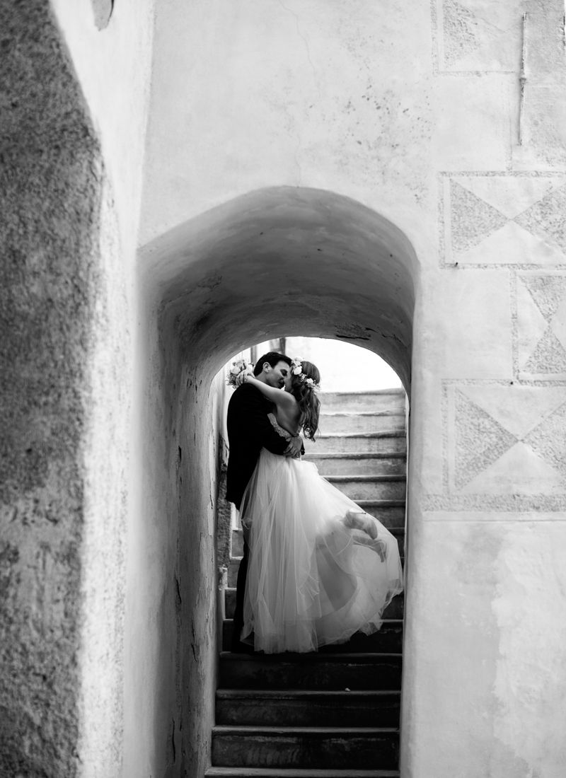 tBride and groom portrait framed by historic stone arch in the Dolomites