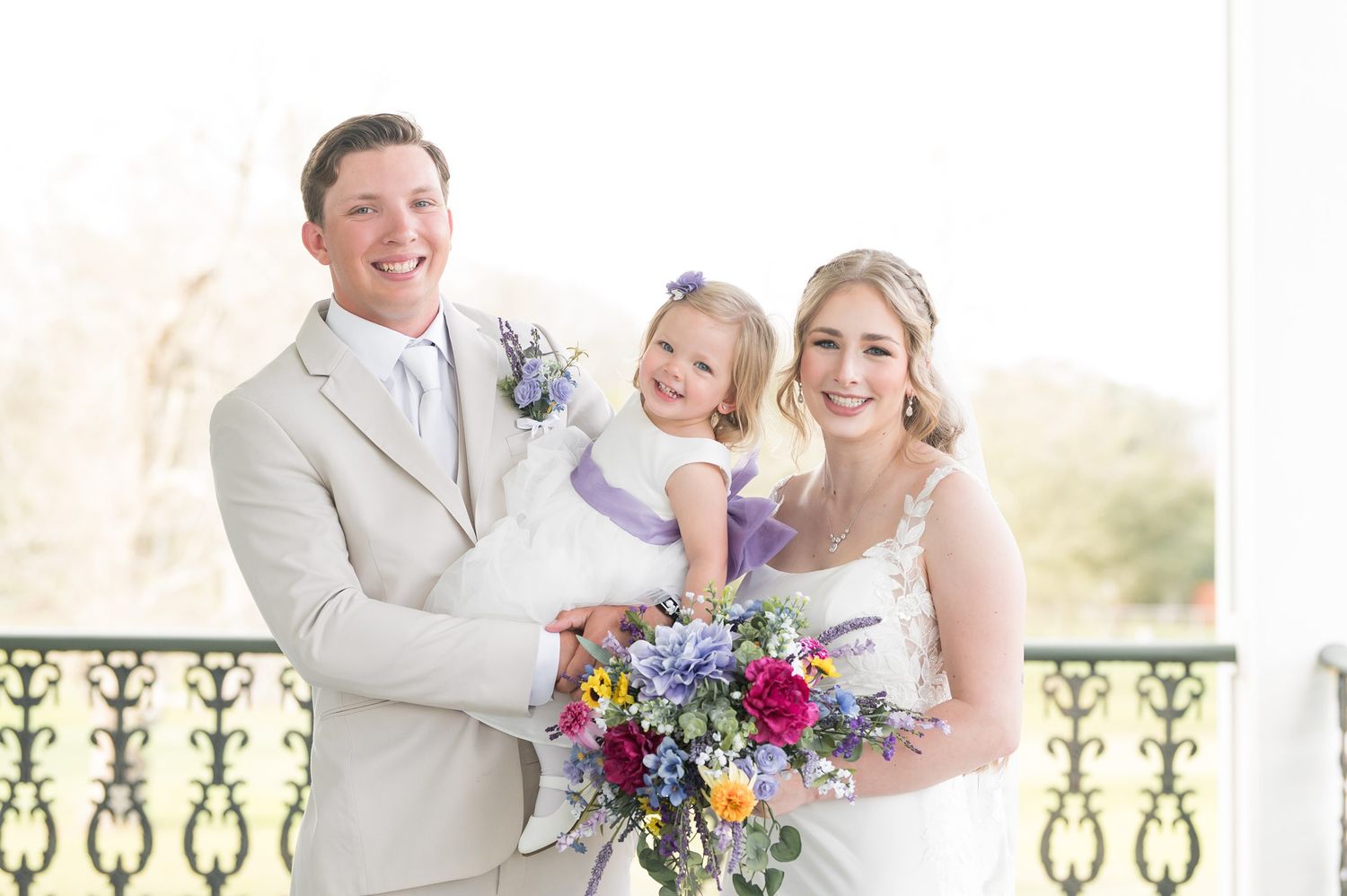 Wedding couple and party members celebrate joyfully outdoors.