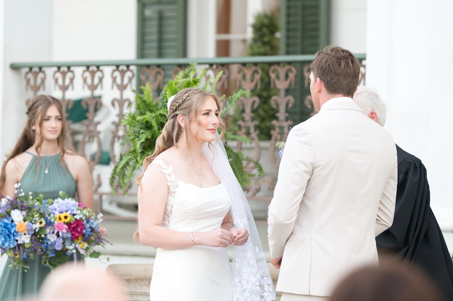 Wedding celebration with colorful floral bouquets and formal attire on mansion grounds.