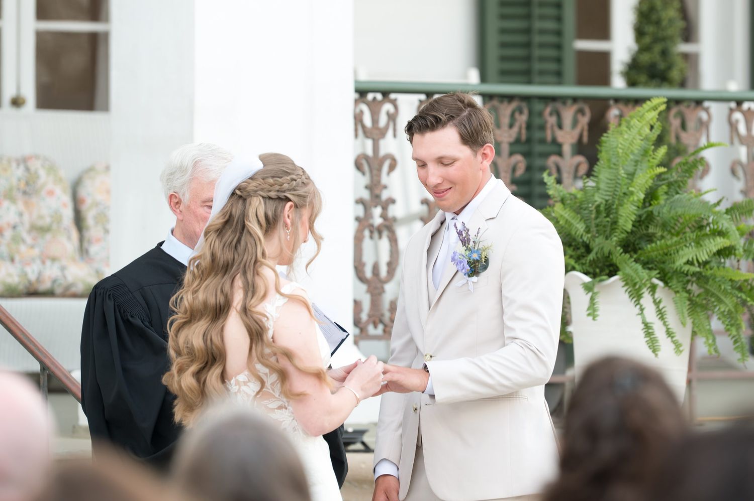 Wedding ceremony taking place on an elegant southern plantation porch with green shutters and ferns.
