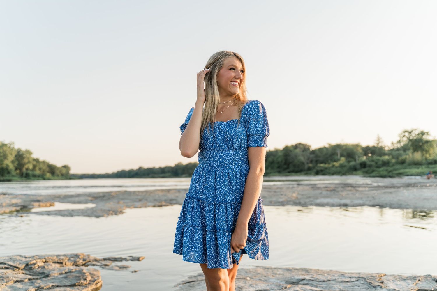 Perrysburg High School senior in blue floral dress walks along scenic beach shoreline at sunset at Side Cut Metropark near Toledo