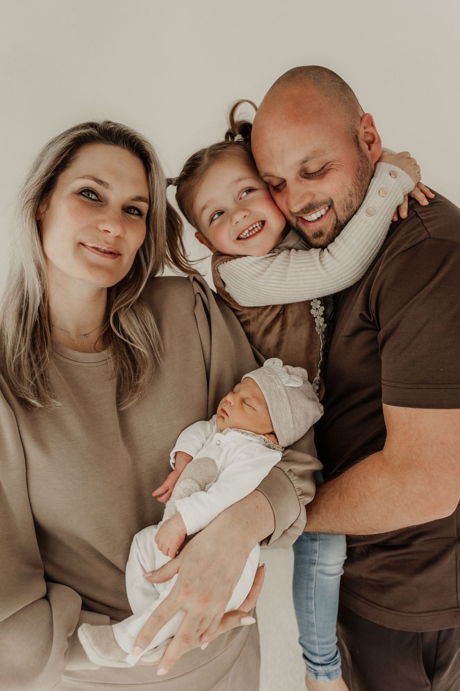 gezin staand met newborn baby tijdens fotoshoot in lichte studio Soest