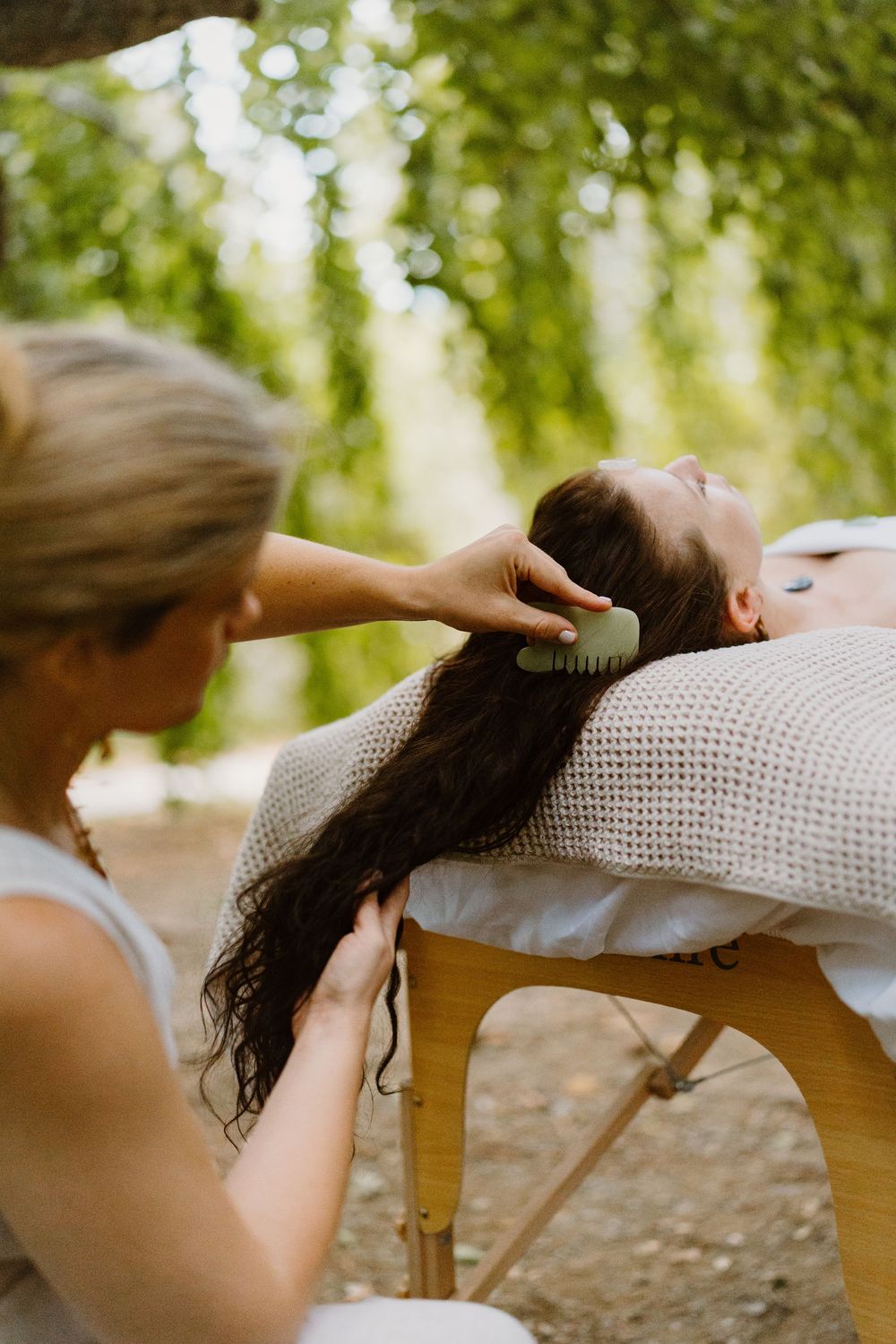 Sequential images of a therapeutic massage session showing hands working on someone resting on a wooden chair in nature.