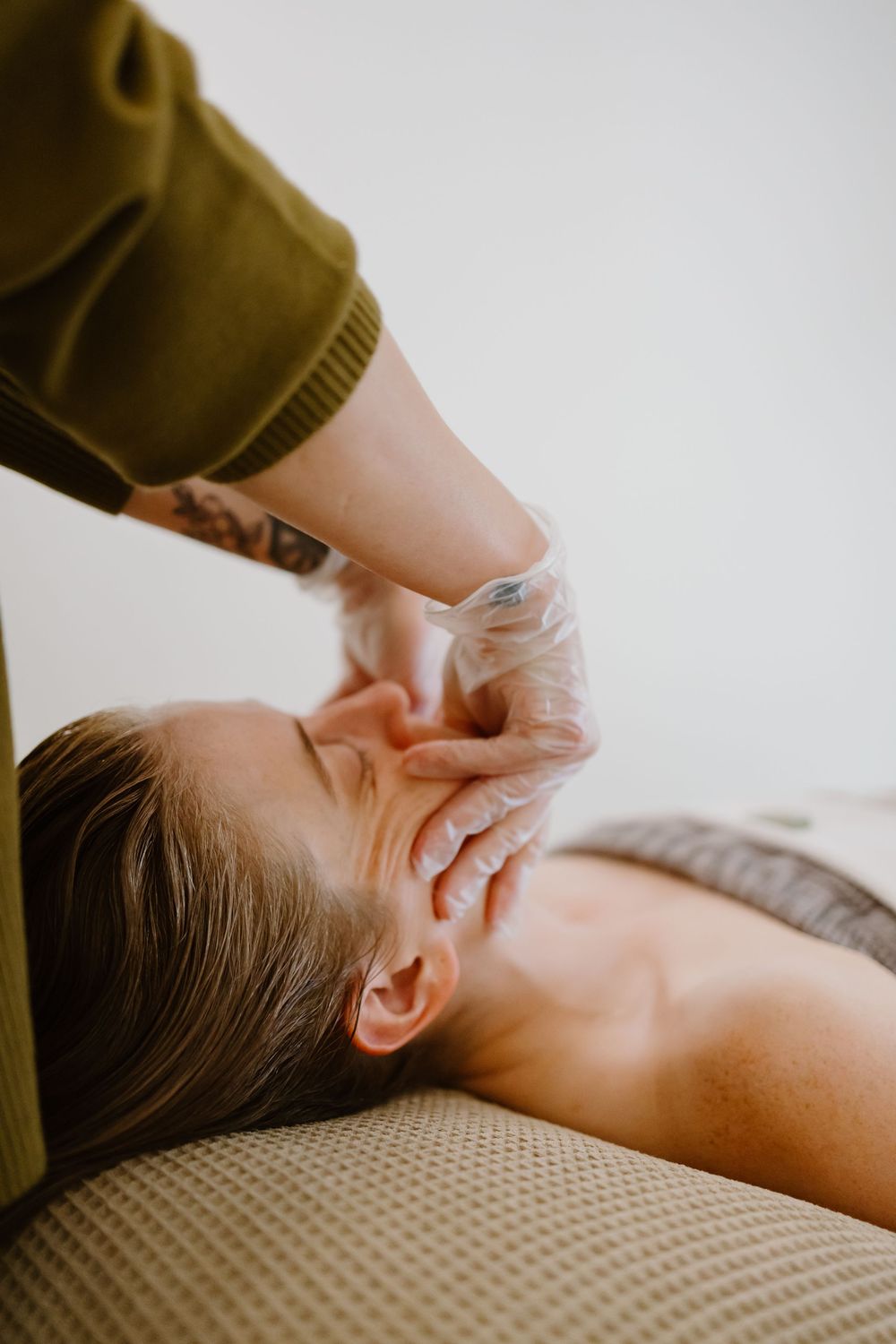 Close-up view of a therapeutic neck massage being performed on a person lying on a textured surface.