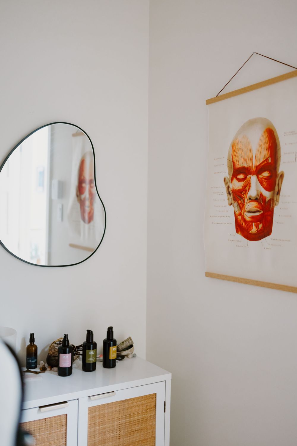 A series of circular mirrors and orange decorative masks mounted on a white wall above white storage cabinets.