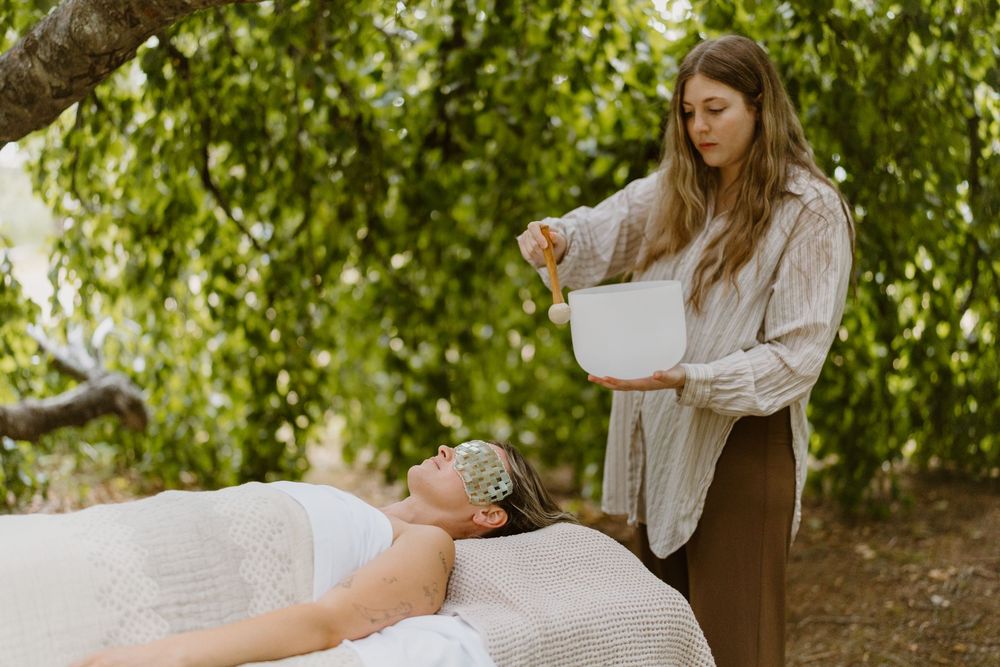 A massage therapist performs a therapeutic treatment on a client in an outdoor spa setting surrounded by lush greenery.