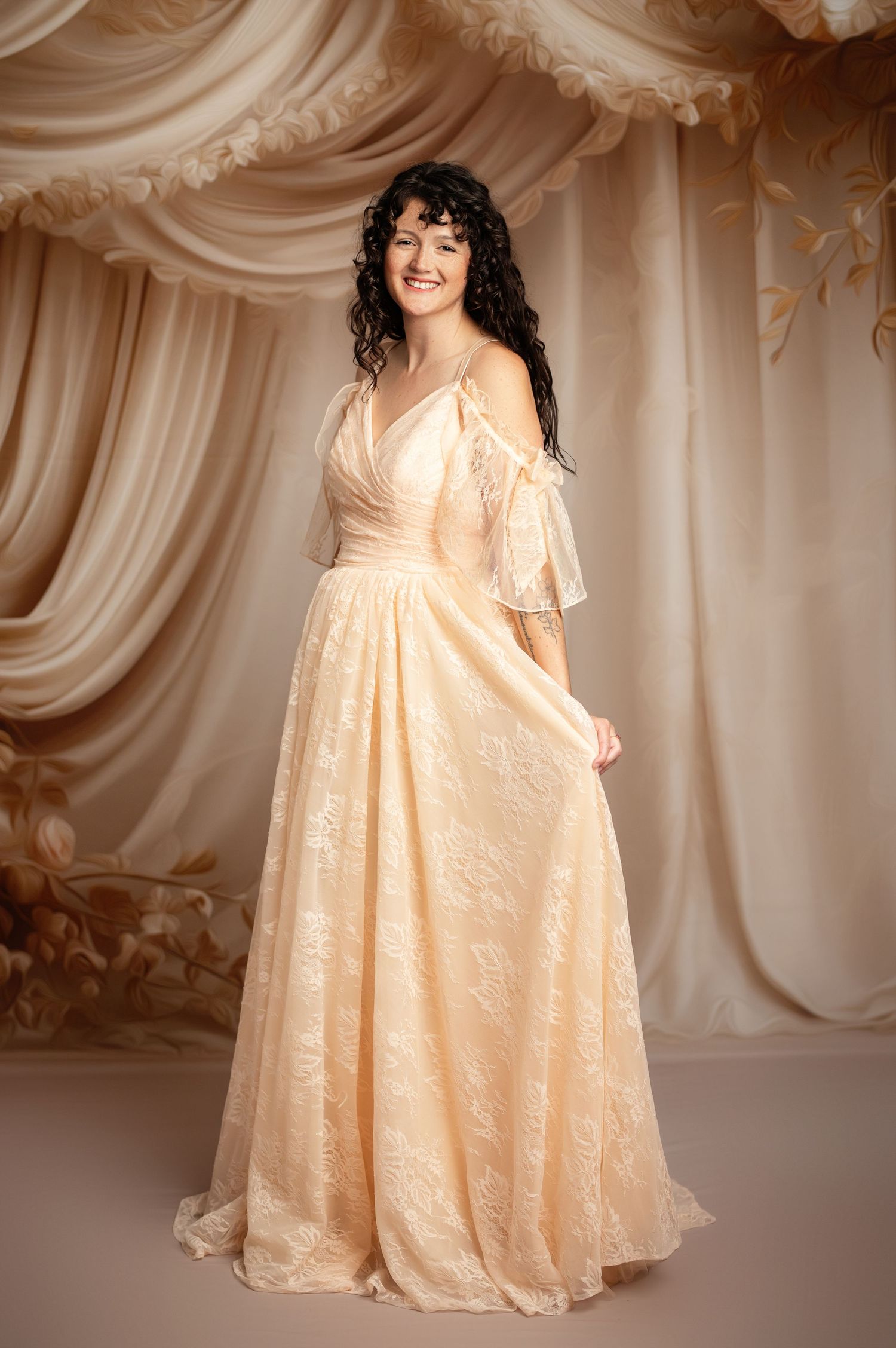 Young ballet dancer in cream tulle dress holds white lantern while posing barefoot against neutral backdrop.