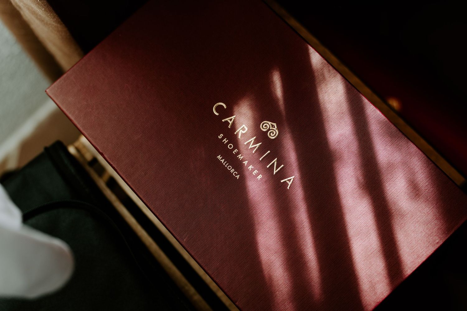 Elegant dark red Carmina Brothers box with gold logo resting on a surface.