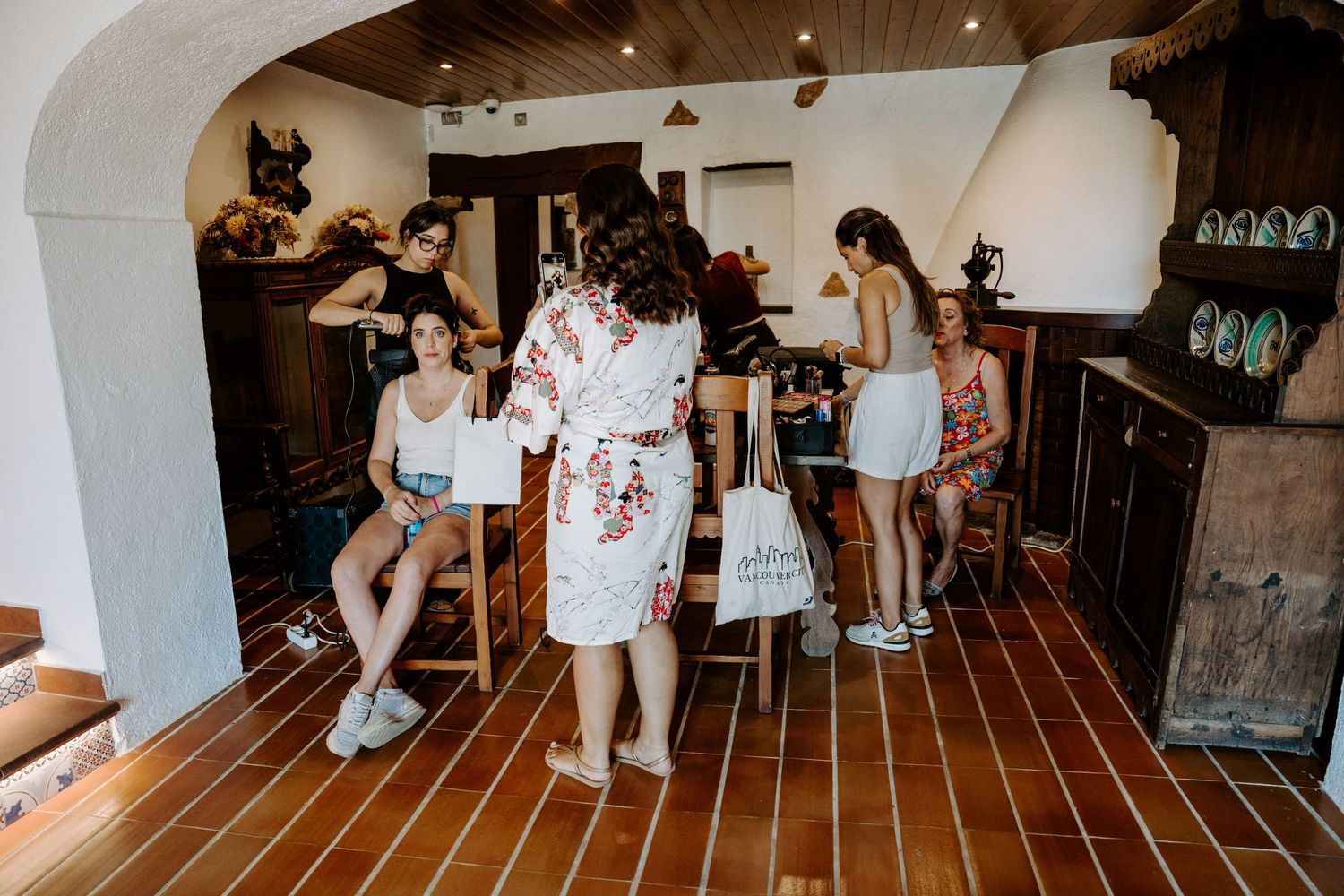 Bridesmaids getting ready in a rustic room with terracotta floors before the wedding ceremony.