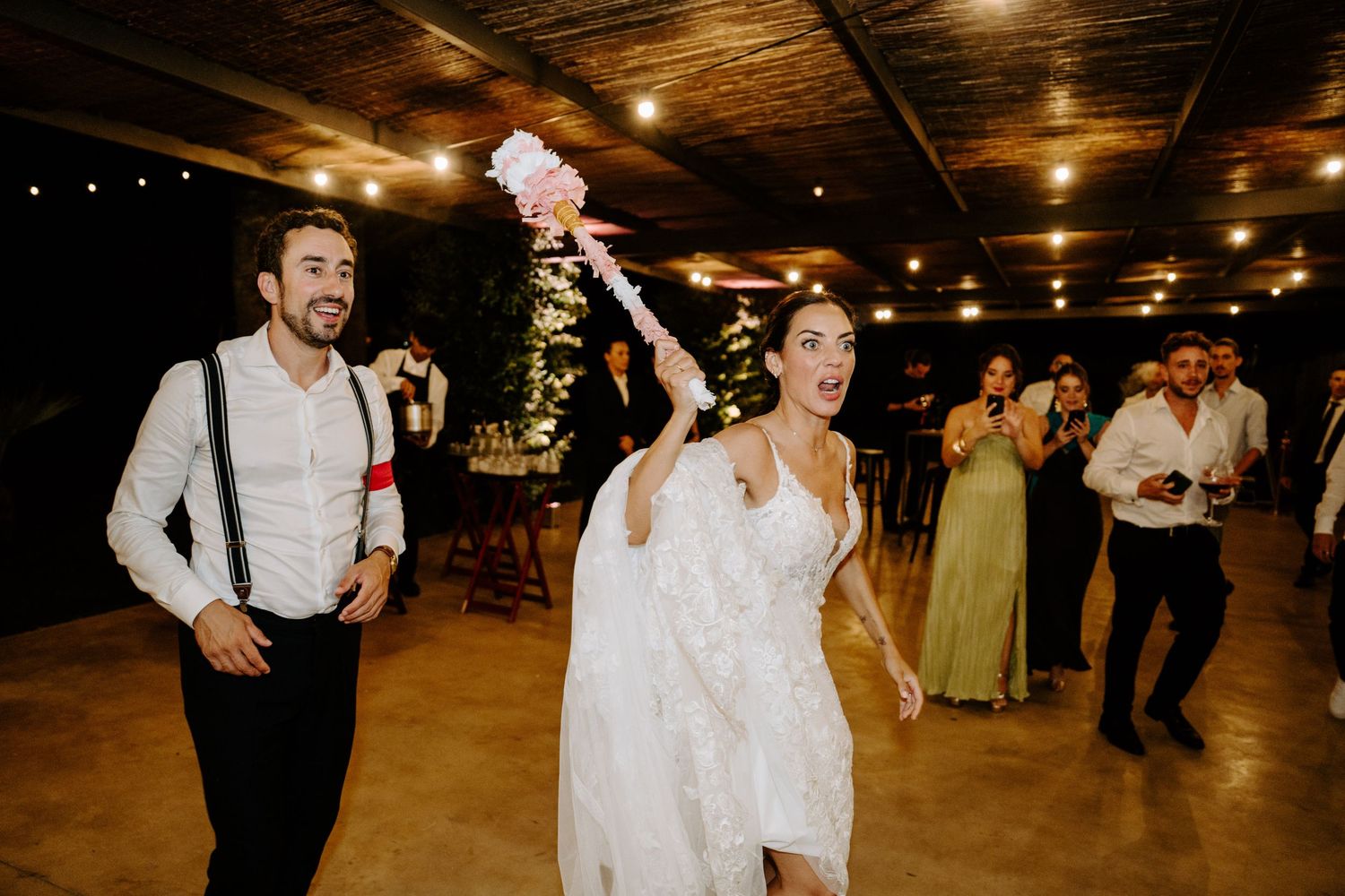 Bride tossing bouquet while groom watches during wedding reception.