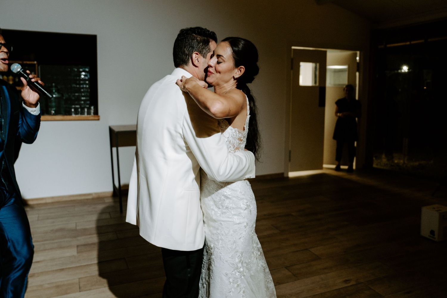 Bride and groom share a tender first kiss during their wedding reception indoors.