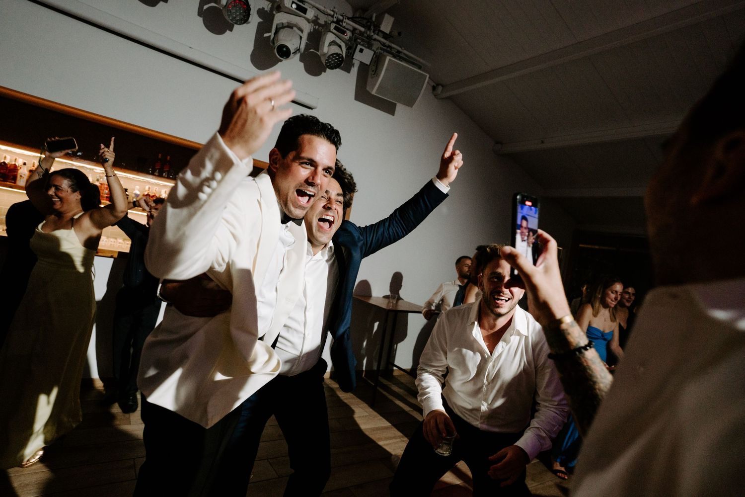 Guests dancing energetically at a wedding reception party.