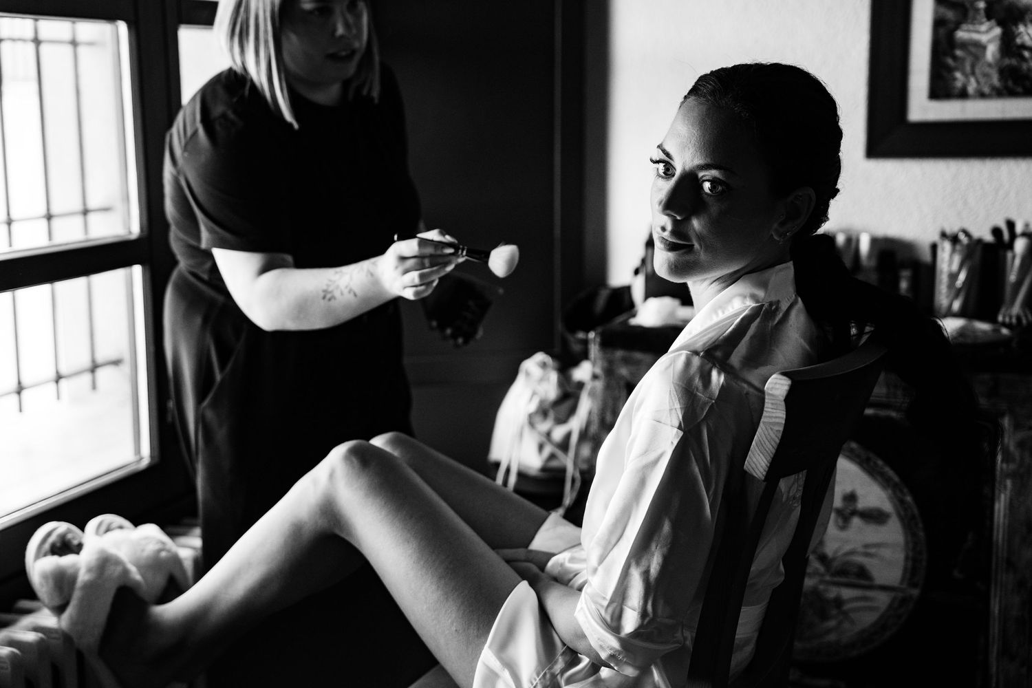 Black and white photo of bride getting makeup done before her wedding ceremony.