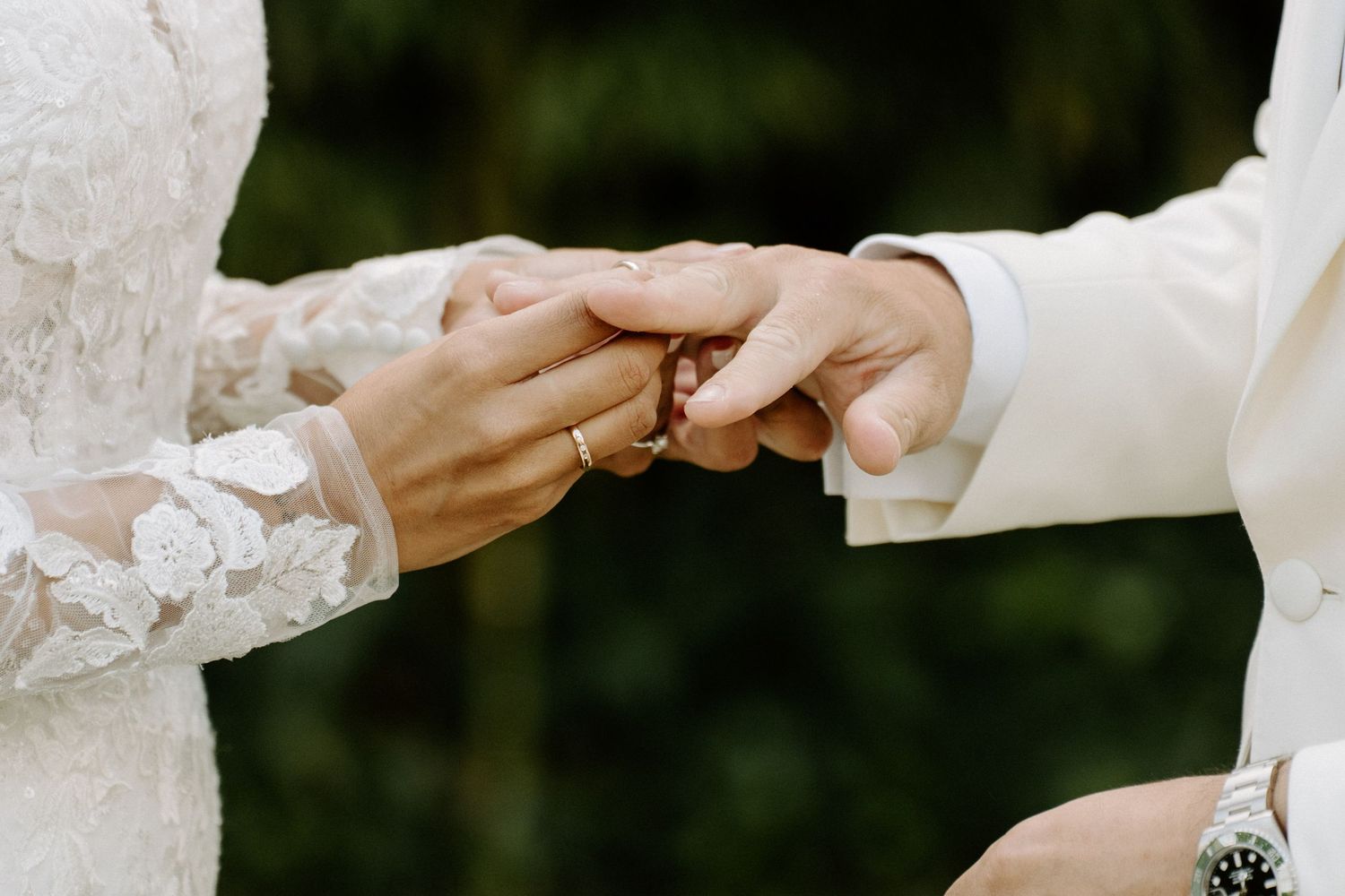 Close-up of a groom placing a wooden wedding ring on the bride's finger during ceremony.