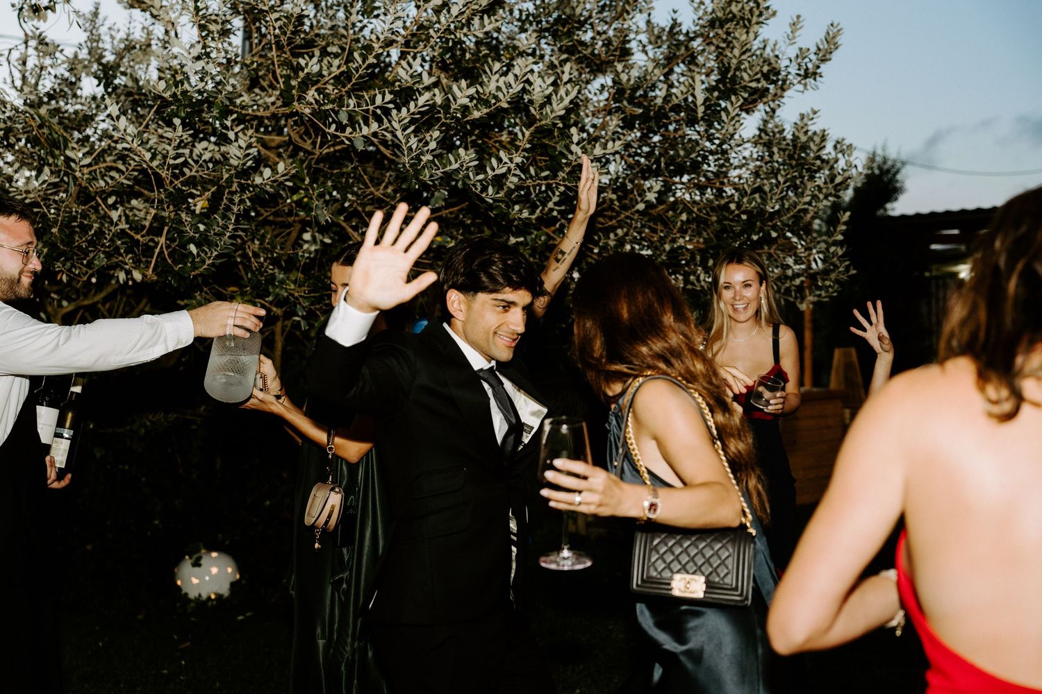 Guests dancing and celebrating outdoors at a wedding reception party at night.