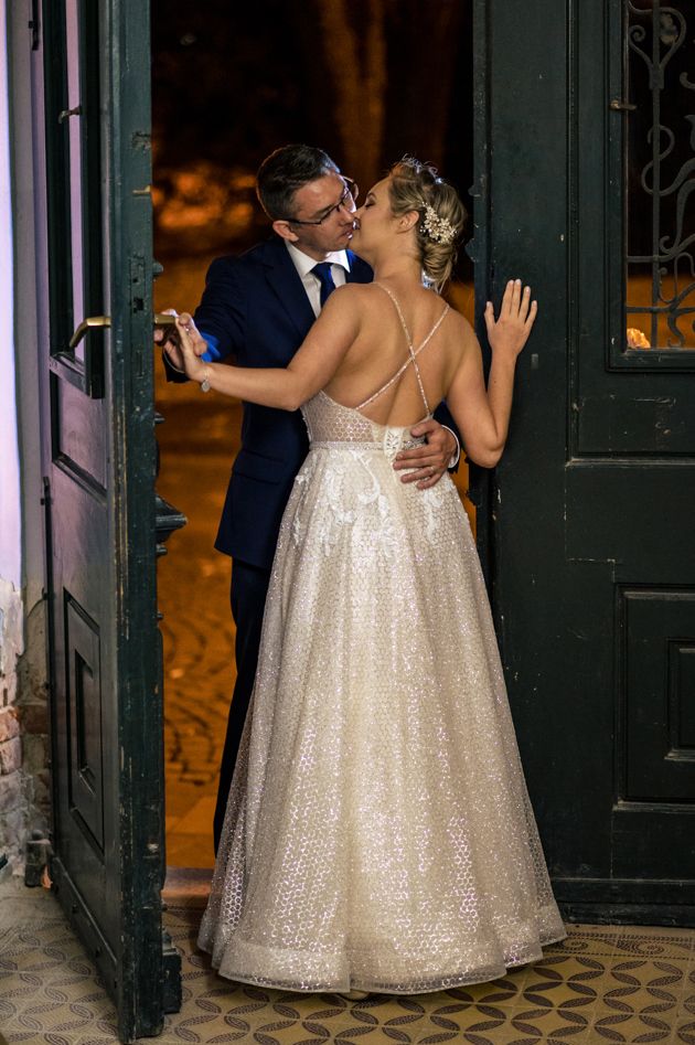 Glamorous wedding couple embracing against vintage green doors in evening light.