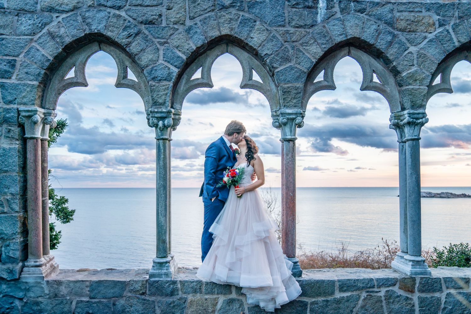 Couple kissing at the iconic Hammond Castle in Gloucester, MA during their wedding photos.