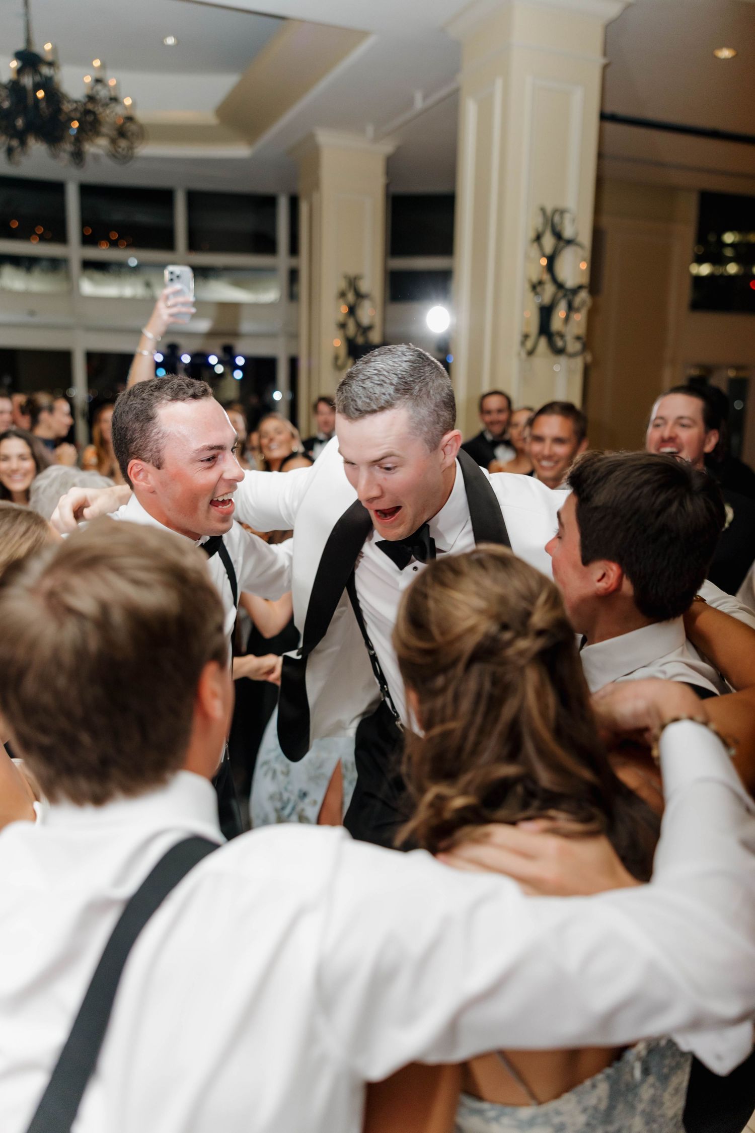 Energetic wedding party dancing and celebrating together in a reception hall with festive atmosphere.