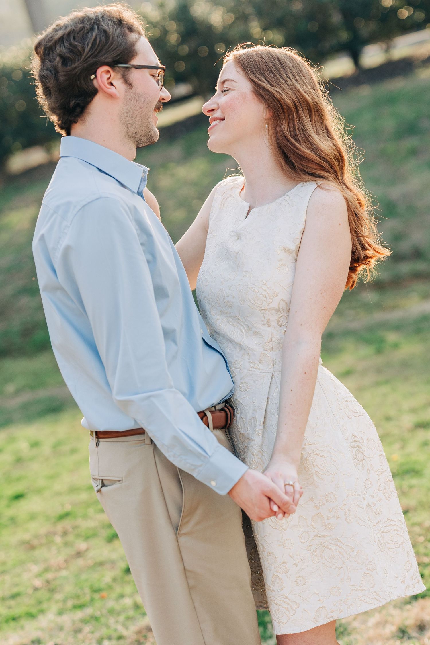 A couple shares intimate moments during a romantic photoshoot in a sunlit outdoor setting.