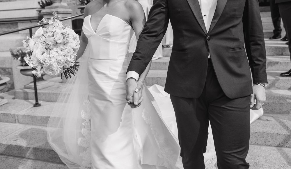 A bride and groom walk hand in hand down stone steps during their wedding ceremony.