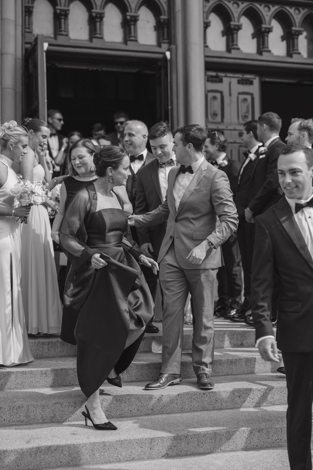 A vintage black and white photo of couples dancing on steps outside an ornate building in formal attire.