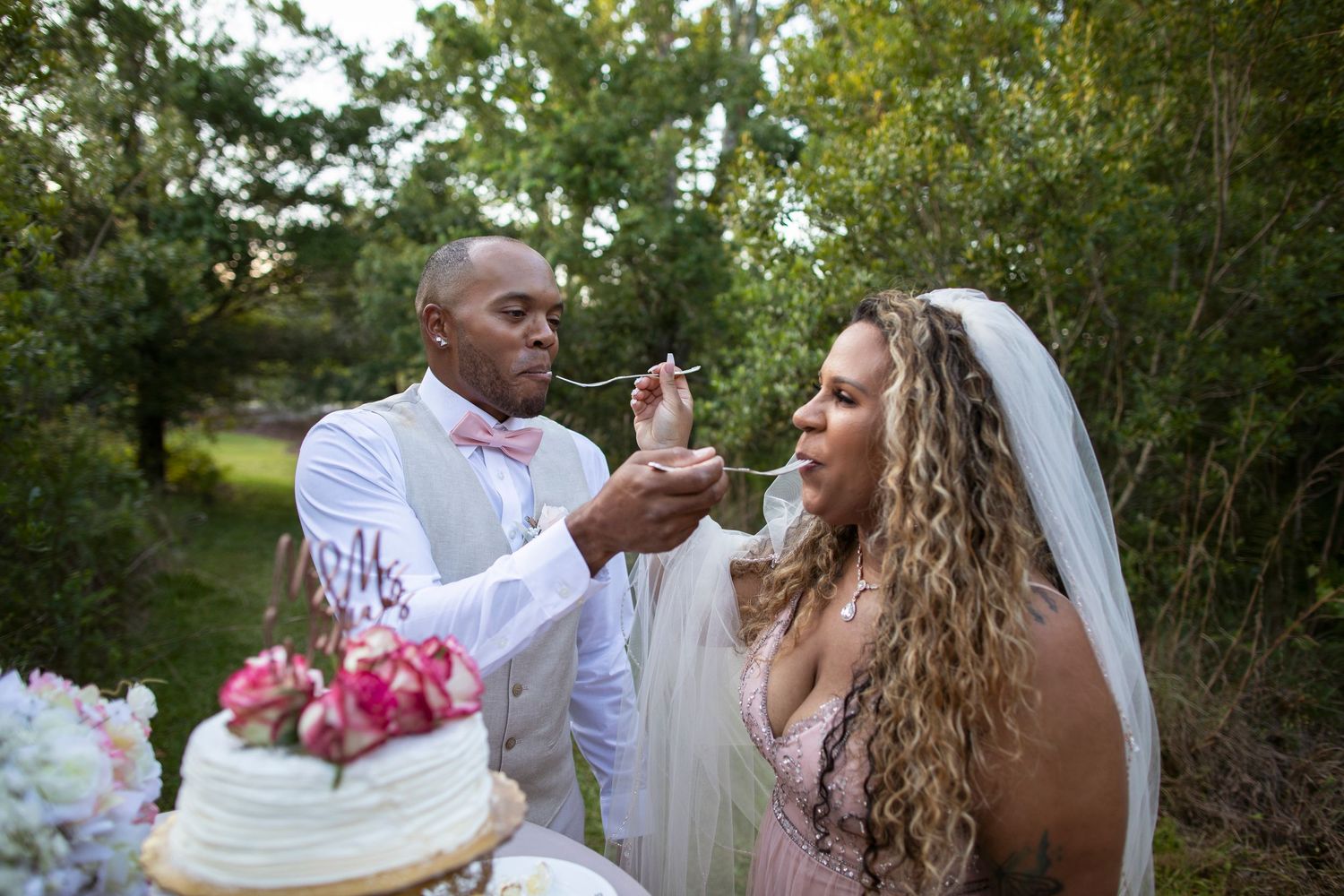 Joyful wedding couple shares playful moments together in a lush garden setting during their celebration.