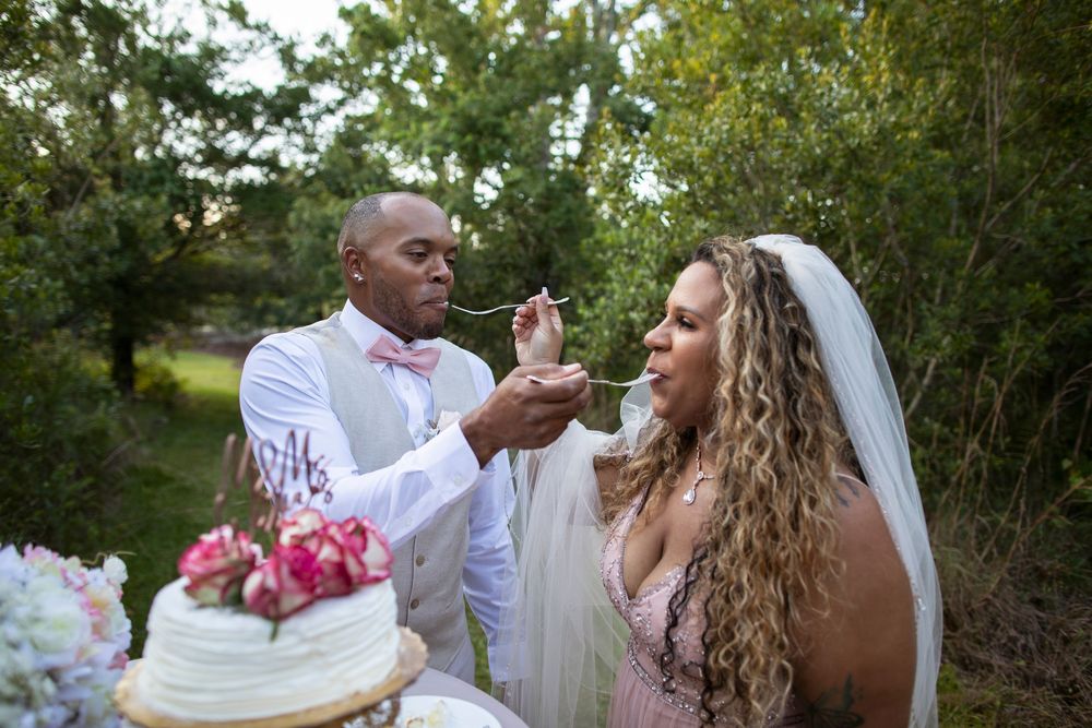 Joyful wedding couple shares playful moments together in a lush garden setting during their celebration.