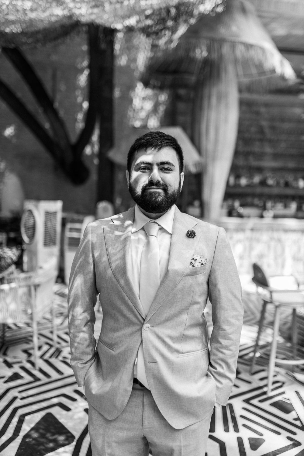A formal portrait of someone wearing a light colored suit and tie in a black and white style.