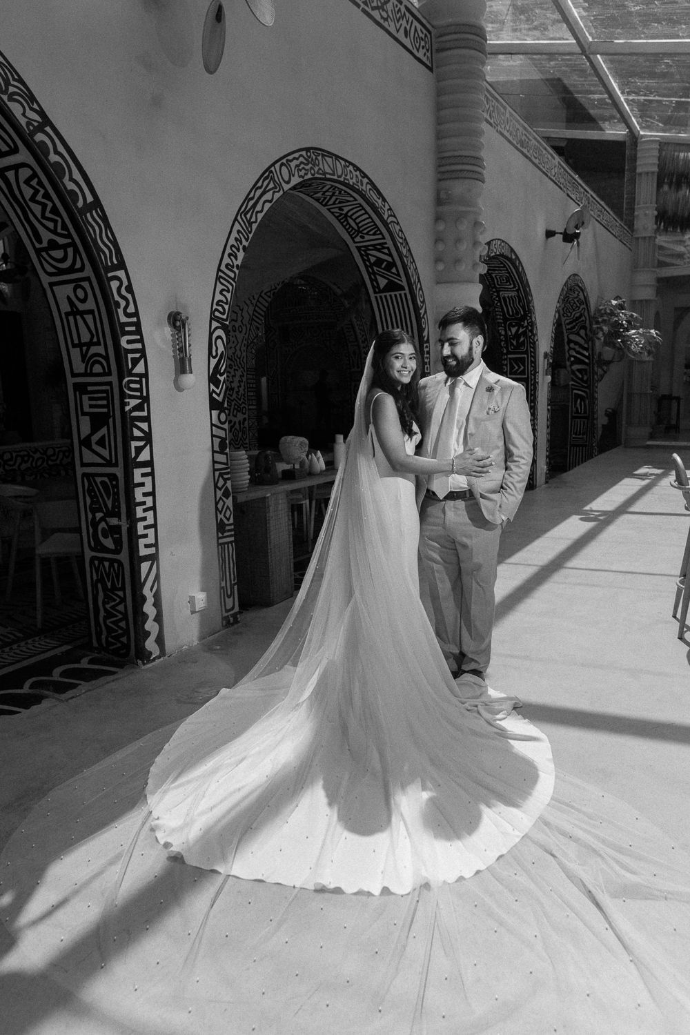 A black and white photo series captures a romantic wedding couple dancing and twirling in an elegant archway setting.