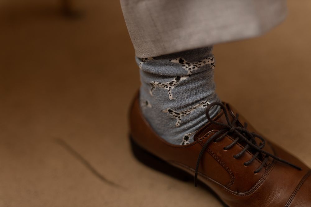 A pair of brown leather oxford dress shoes shown from multiple angles on a beige background.