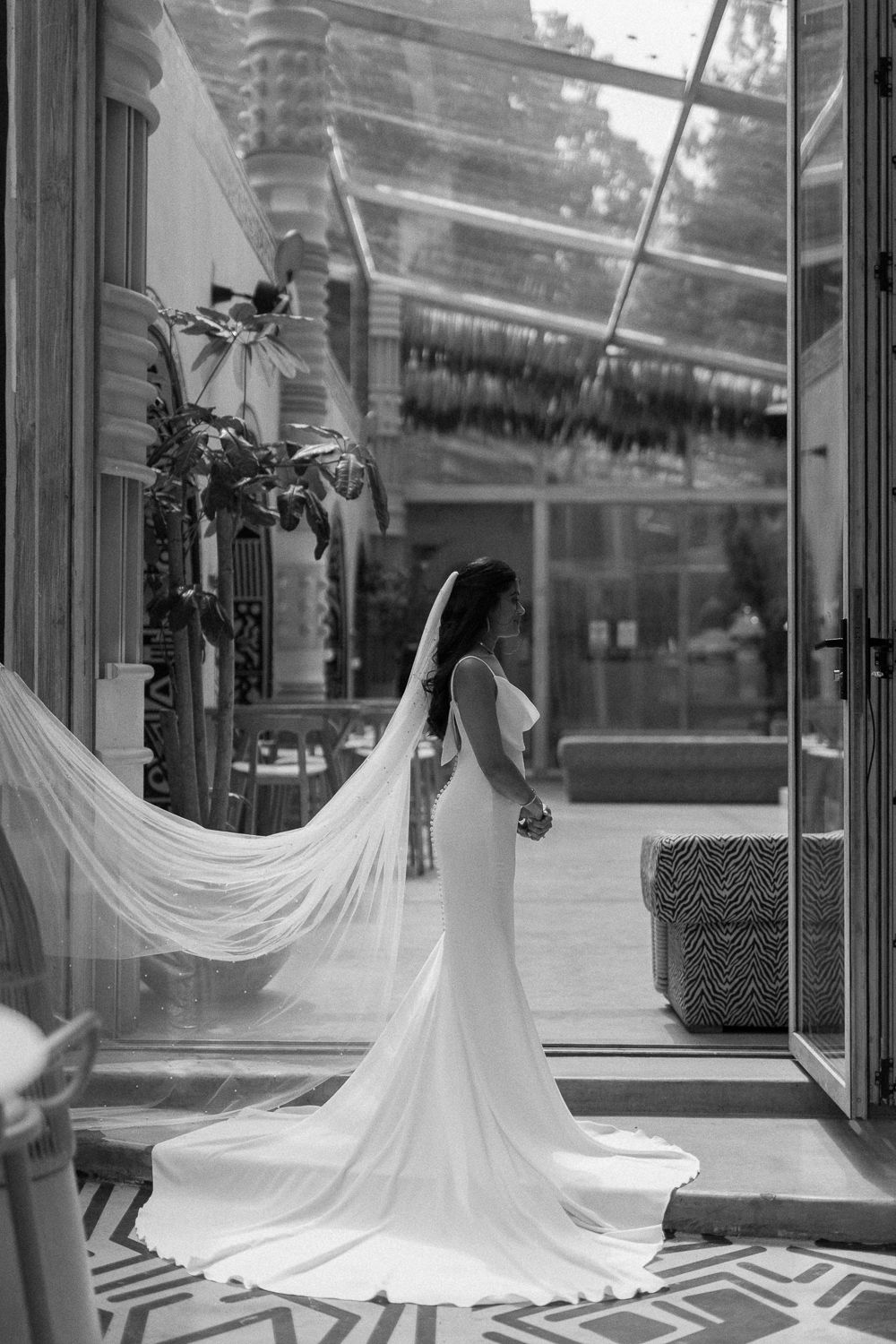 Black and white wedding photography showing flowing white bridal gown train displayed across geometric floor pattern.